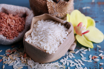 Fototapeta na wymiar Different types of rice in sacks on wooden background