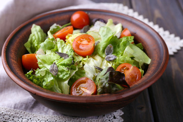 Salad with arugula and cherry tomatoes on wooden table