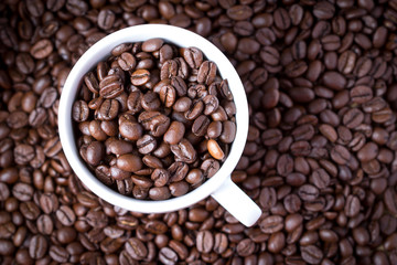 Coffee beans in coffee cup. Macro close up.
