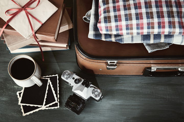 Vintage suitcase with clothes and books on wooden background