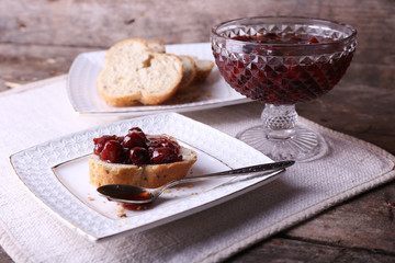 Fresh bread with jam on plate on wooden background