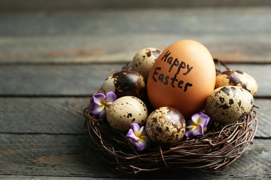 Bird eggs with decorative flowers in nest on wooden background