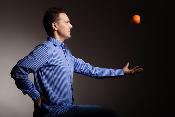Diet and healthy nutrition. Man throwing orange