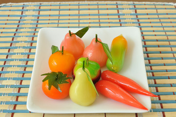 Deletable imitation fruits in white plate on mat, orange, tomato