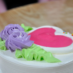 White creamy cake and violet flowers green leaf heart-shaped dec