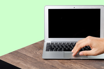 hand using a laptop on wood table, green color background