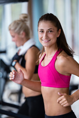 Fototapeta na wymiar friends exercising on a treadmill at the bright modern gym