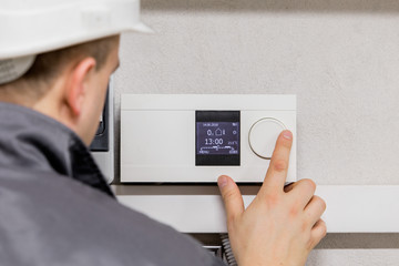 Engineer adjusting thermostat for automated heating system