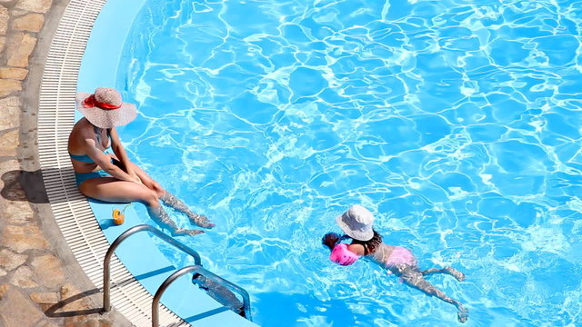 Woman with a child enjoying on vacation in a swimming pool