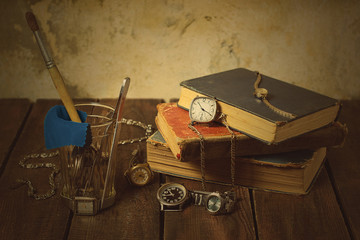 Old clocks, books, glass, tools on a wooden background