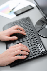 close up of hands detail typing on a desktop computer keyboard
