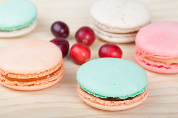 French Macarons with cranberries on wooden background