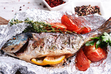 Tasty baked fish in foil on table close-up