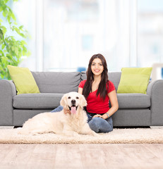 Woman sitting by a sofa with her dog at home