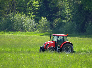 red tractor mows the grass