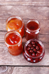 Homemade jars of fruits jam on rustic wooden background