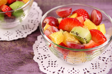 Fruit salad with in glassware on color wooden background