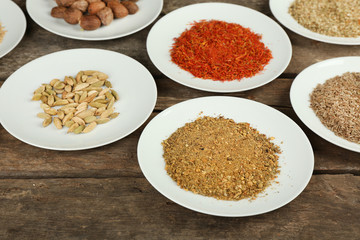 Different spices on plates, on old wooden table