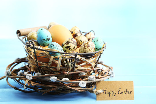 Bird eggs in wicker basket on color wooden background