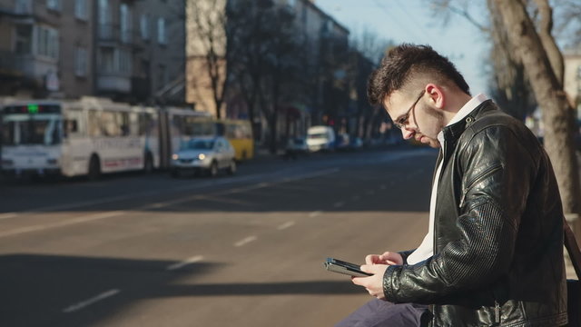 Young businessman using a tablet on a bench in the city