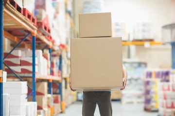Worker carrying boxes in warehouse