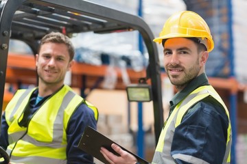 Smiling warehouse worker and forklift driver