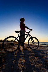 Fototapeta premium silhouette of woman biking at sunset