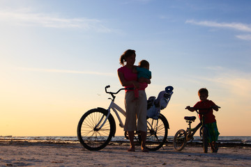 mother with kids biking at sunset