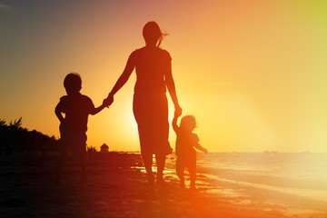 Fototapeta premium mother and two kids walking on at sunset