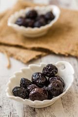 Fototapeta na wymiar Marinated Black Olives on White Wooden Background