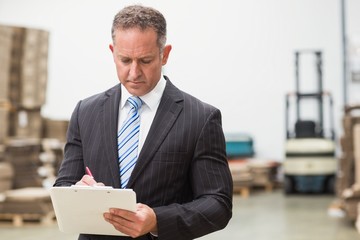 Serious boss writing on clipboard