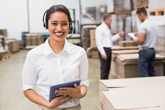 Warehouse manager wearing headset holding clipboard