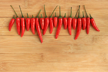 Row of red thai chili peppers on wood background - 78765086