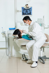 asian dentist is doing a dental checkup to a young asian woman - 78765862