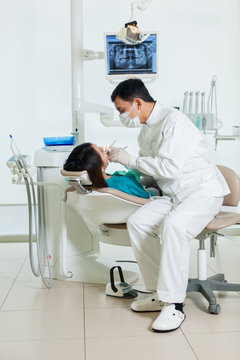 asian dentist is doing a dental checkup to a young asian woman