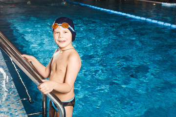 Young boy using ladder to exit swimming pool