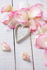 Heart on petals on wooden background