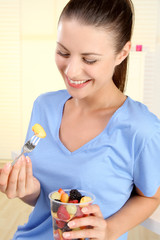 Obraz na płótnie Canvas Junge Frau isst einen Obstsalat