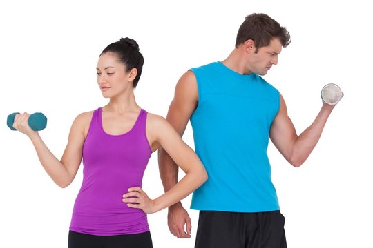 Fit man and woman lifting dumbbells
