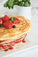 White plate full of pancakes with raspberries strawberries blueb