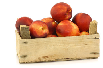 fresh nectarines in a wooden crate on a white background