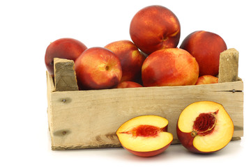 fresh nectarines in a wooden crate on a white background