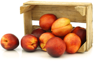 fresh nectarines in a wooden crate on a white background