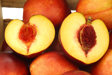 fresh nectarines and a cut one in a wooden crate