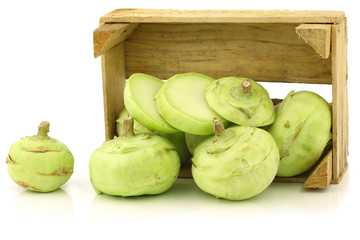 freshly harvested kohlrabi in a wooden crate on a white backgrou
