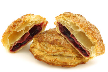 puff pastry cherry turnovers and a cut one on a white background