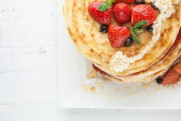 White plate full of pancakes with raspberries strawberries blueb