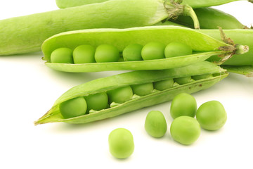 opened green pea pods with peas visible on a white background