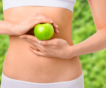 Slim woman in white underwear with green apple at her hands over