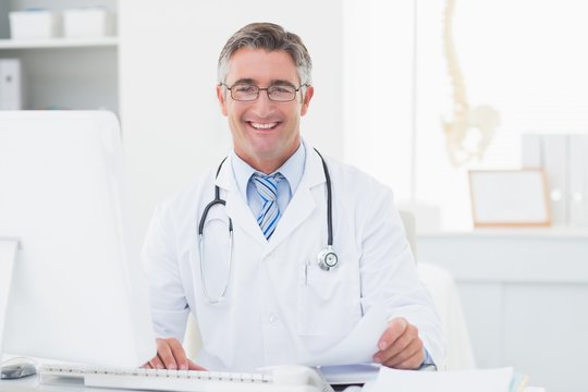 Happy male doctor reviewing documents at table